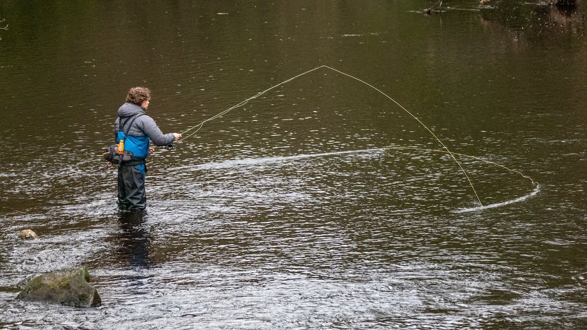 Angler float fishing on a river at golden hour